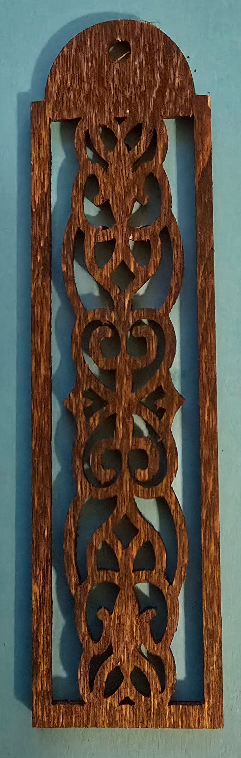 A dark stained wooden bookmark with a Celtic design.