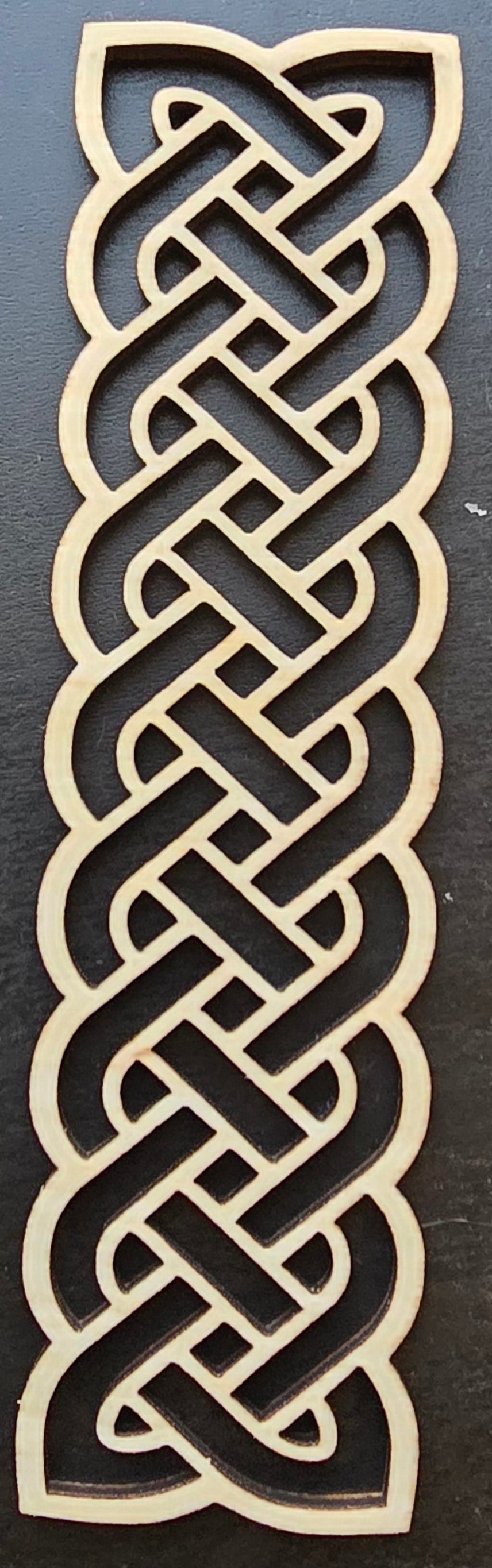 A laser engraved wooden bookmark with a Celtic knot design.