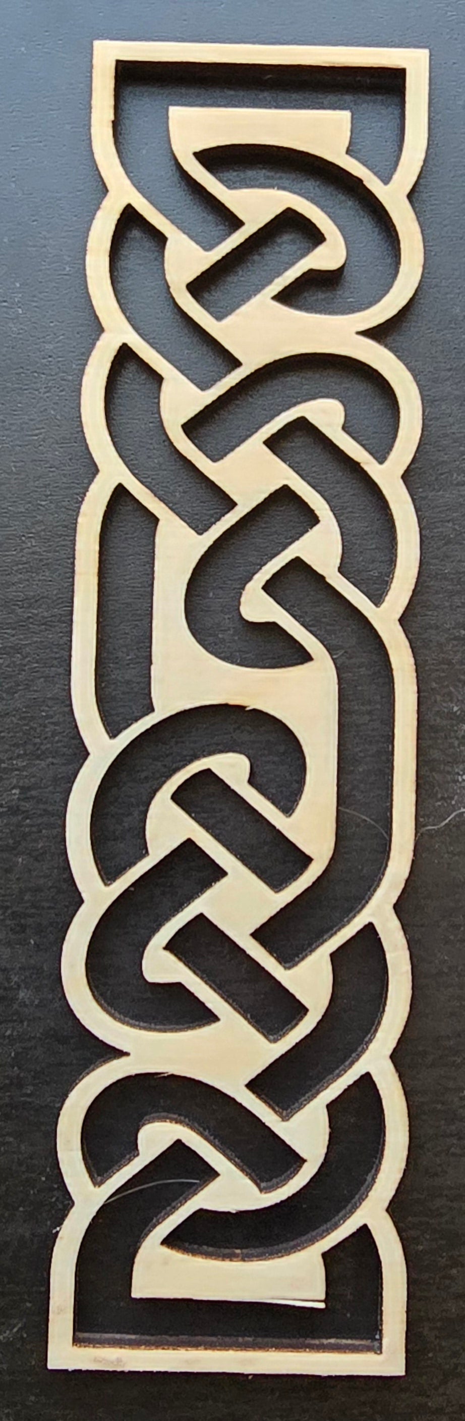 A laser engraved wooden bookmark with a Celtic knot design.