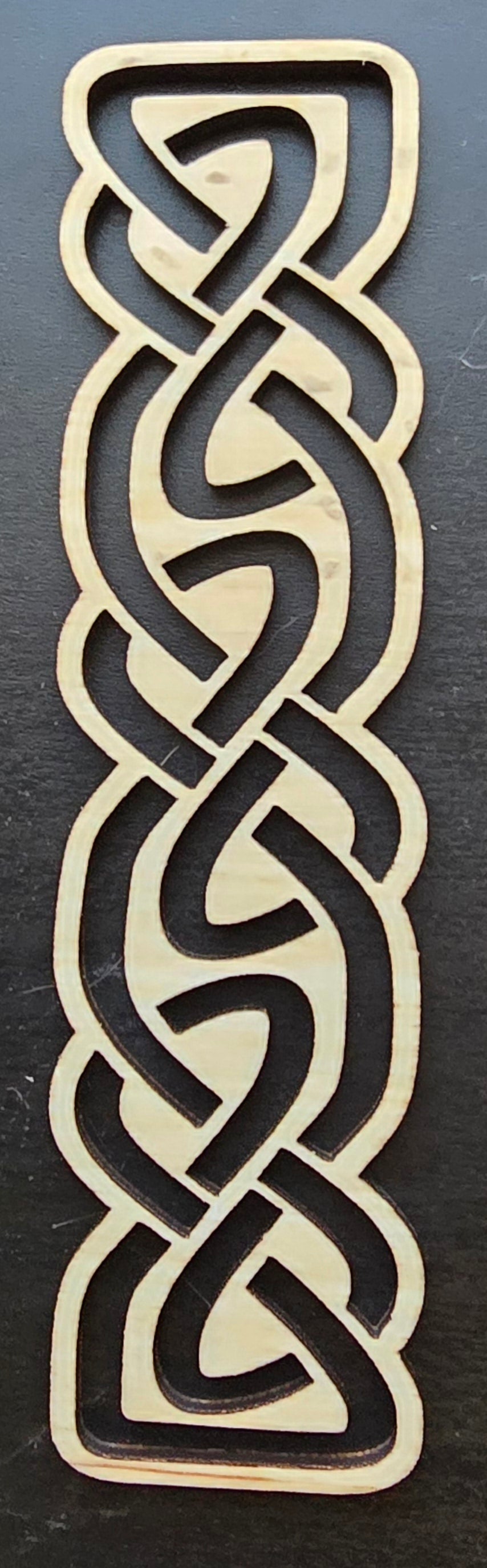 A laser engraved wooden bookmark with a Celtic knot design.