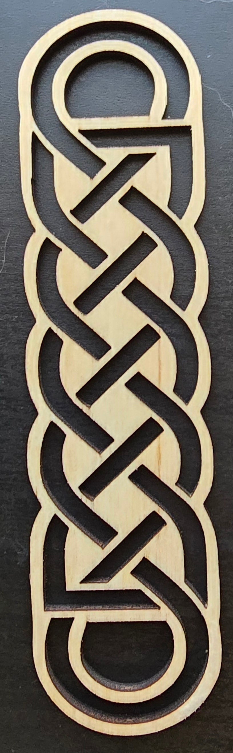 A laser engraved wooden bookmark with a Celtic knot design.