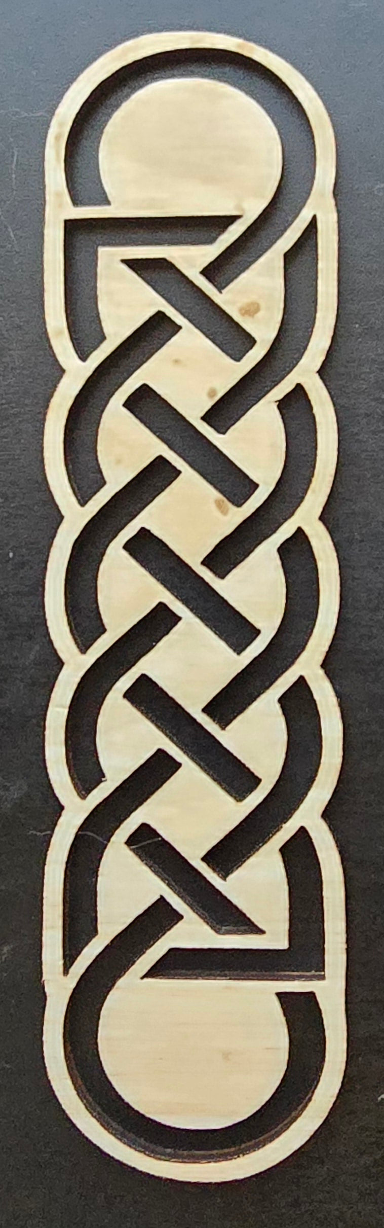 A laser engraved wooden bookmark with a Celtic knot design.