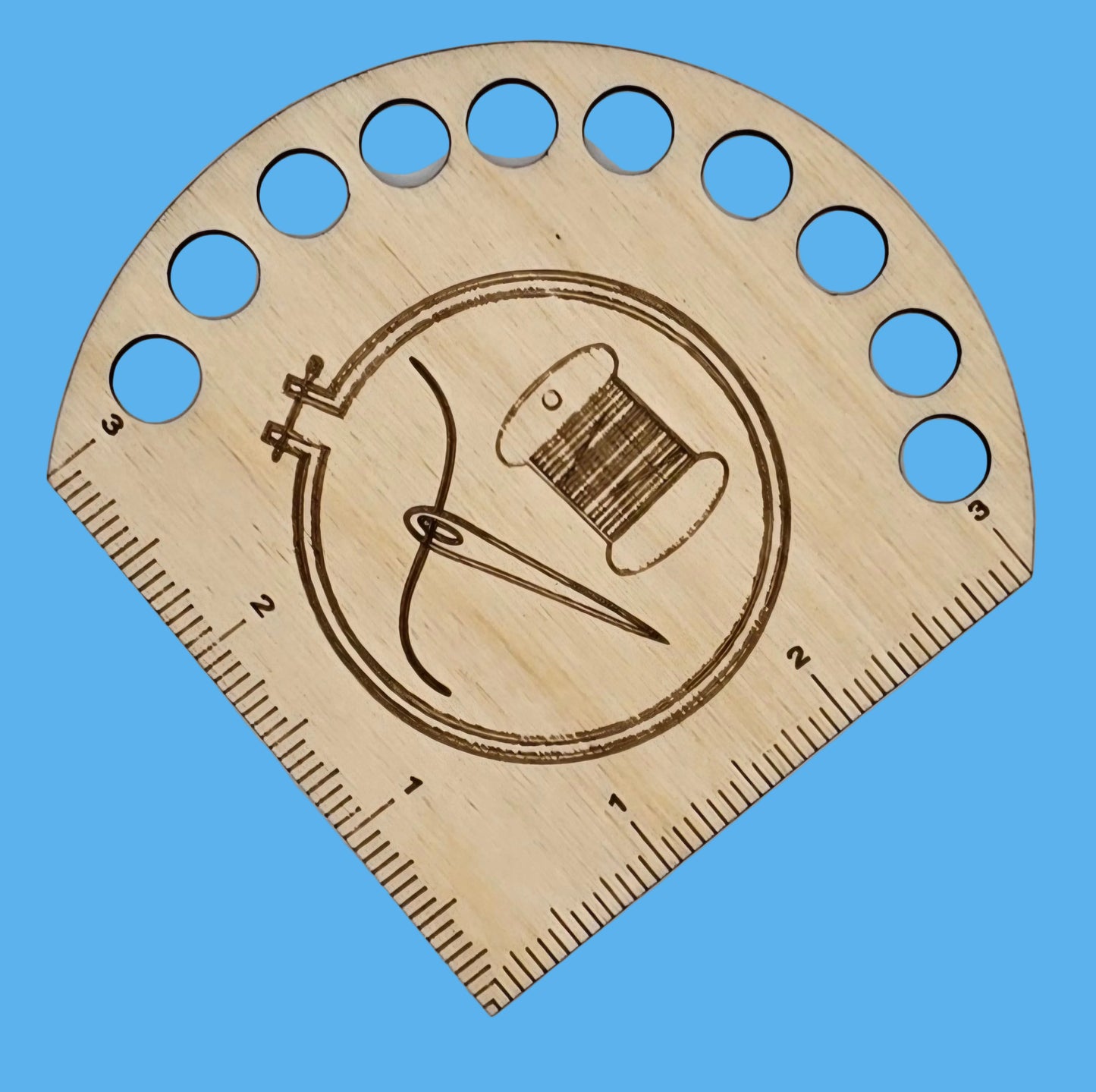 A wooden needle gauge with a whimsical design featuring a needle and thread, and measurement markings.