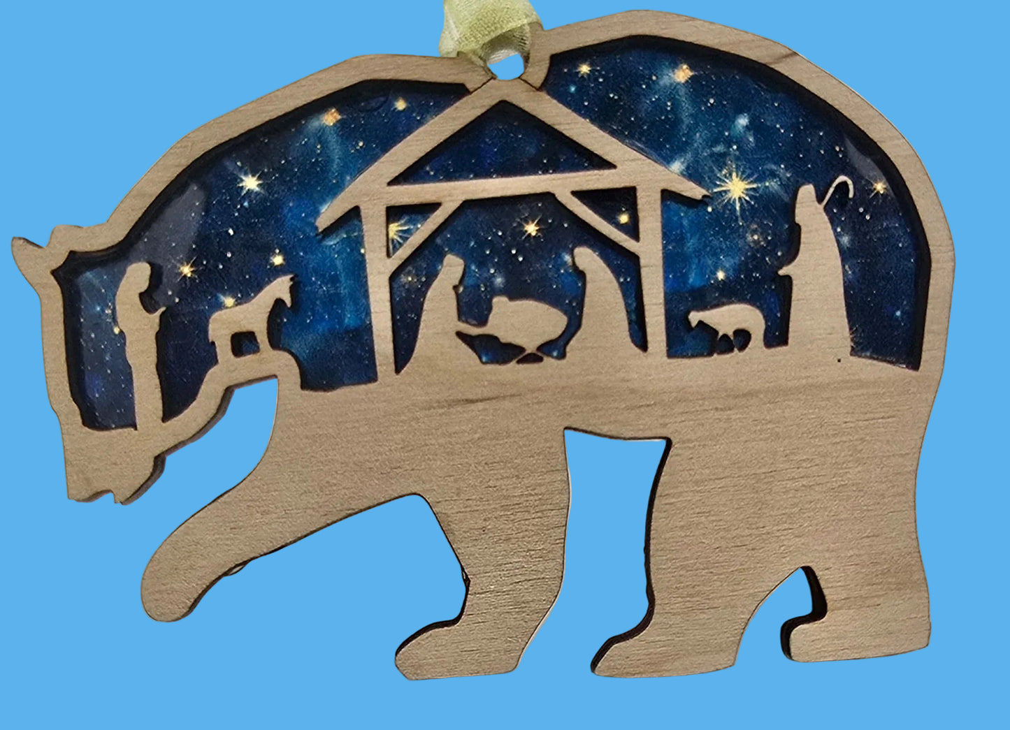 Decorative ornament shaped like a bear with a nativity scene inside on a white background