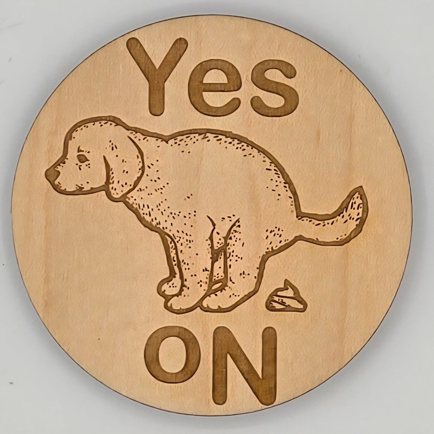 Wooden disc with a dog illustration and 'Yes ON' text on a gray background