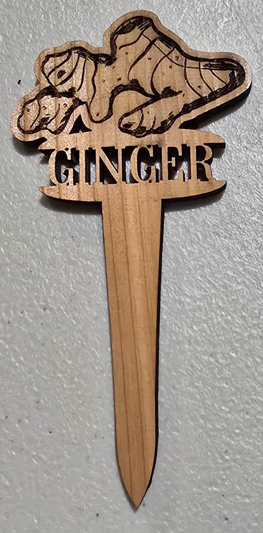 Wooden stake with a laser-cut design on a light gray background