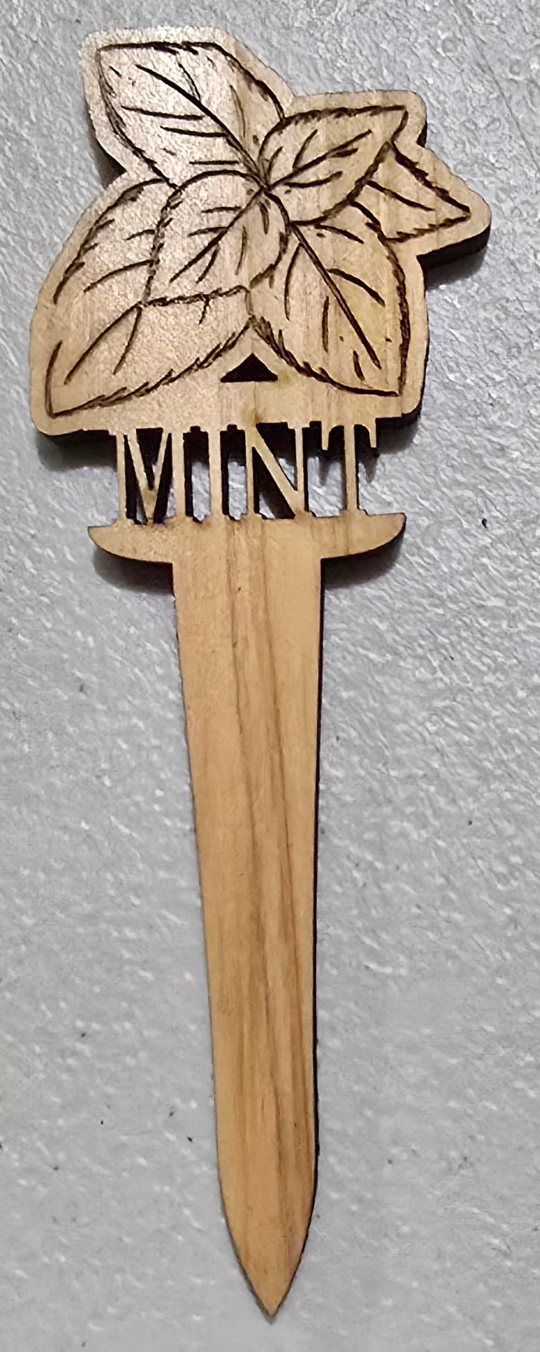 Wooden mint plant marker design on a gray surface