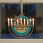Hanukkah ornament with menorah design and reflection of candles.