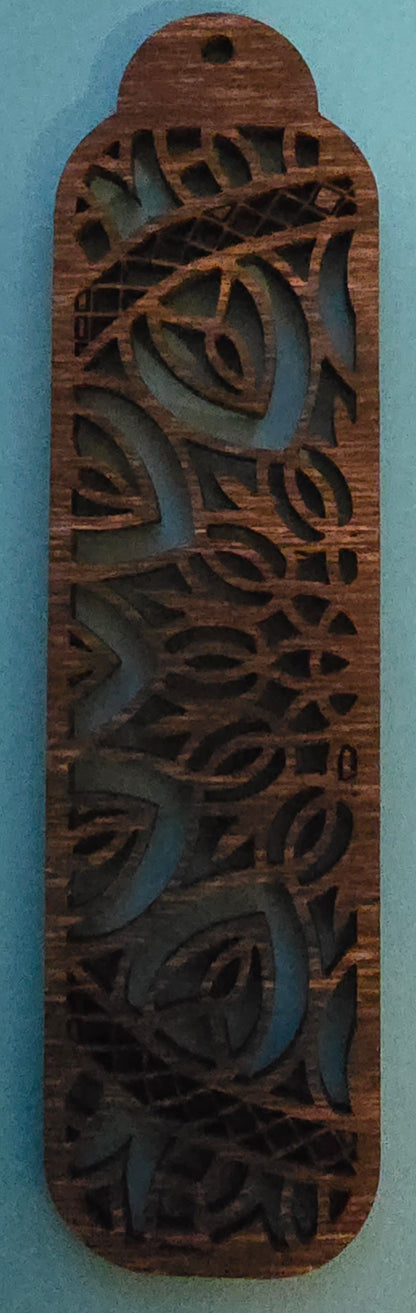 A dark stained wood bookmark with a half circle shape and a mandala-like intricate design.