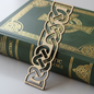 Gold Celtic knot bookmark on a green book with gold text