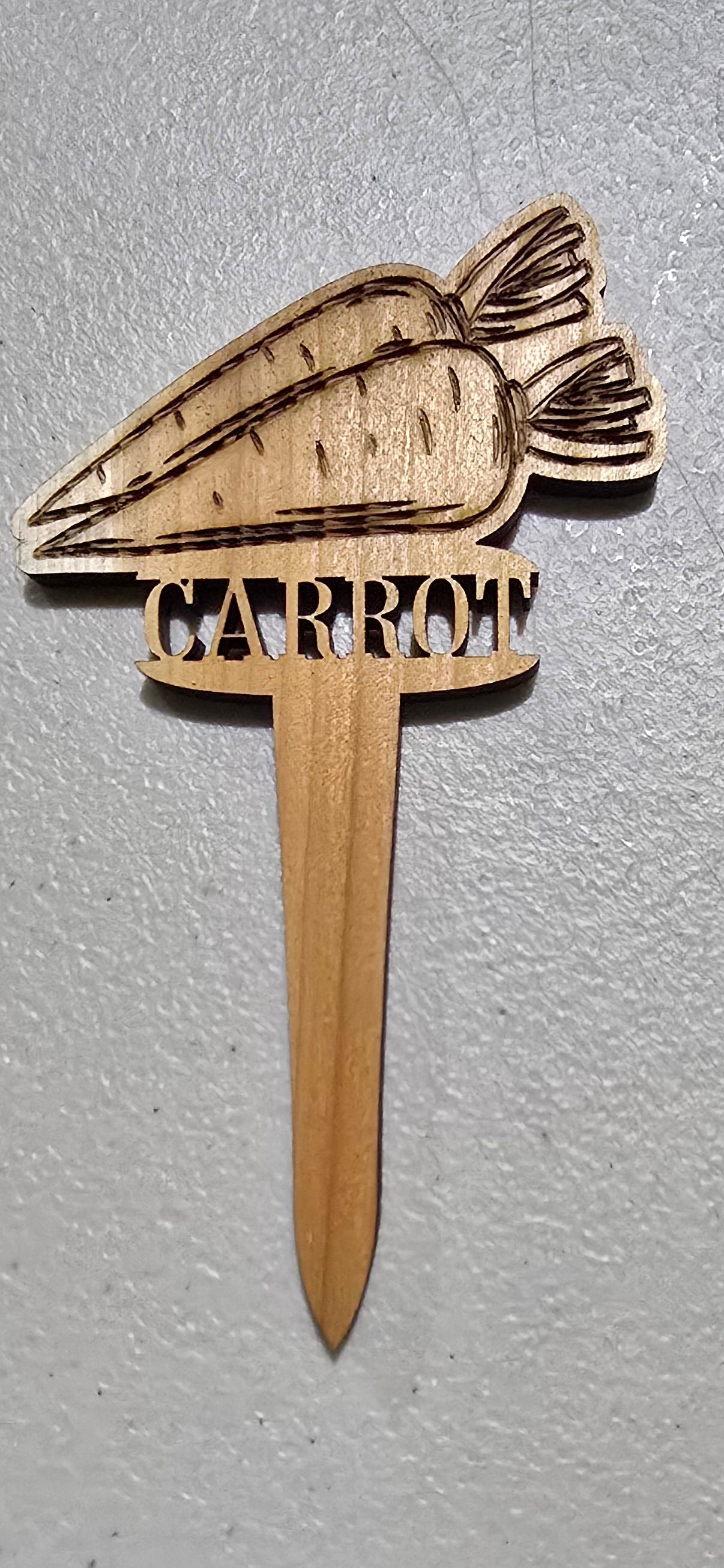 Wooden carrot-shaped tool on a light gray surface
