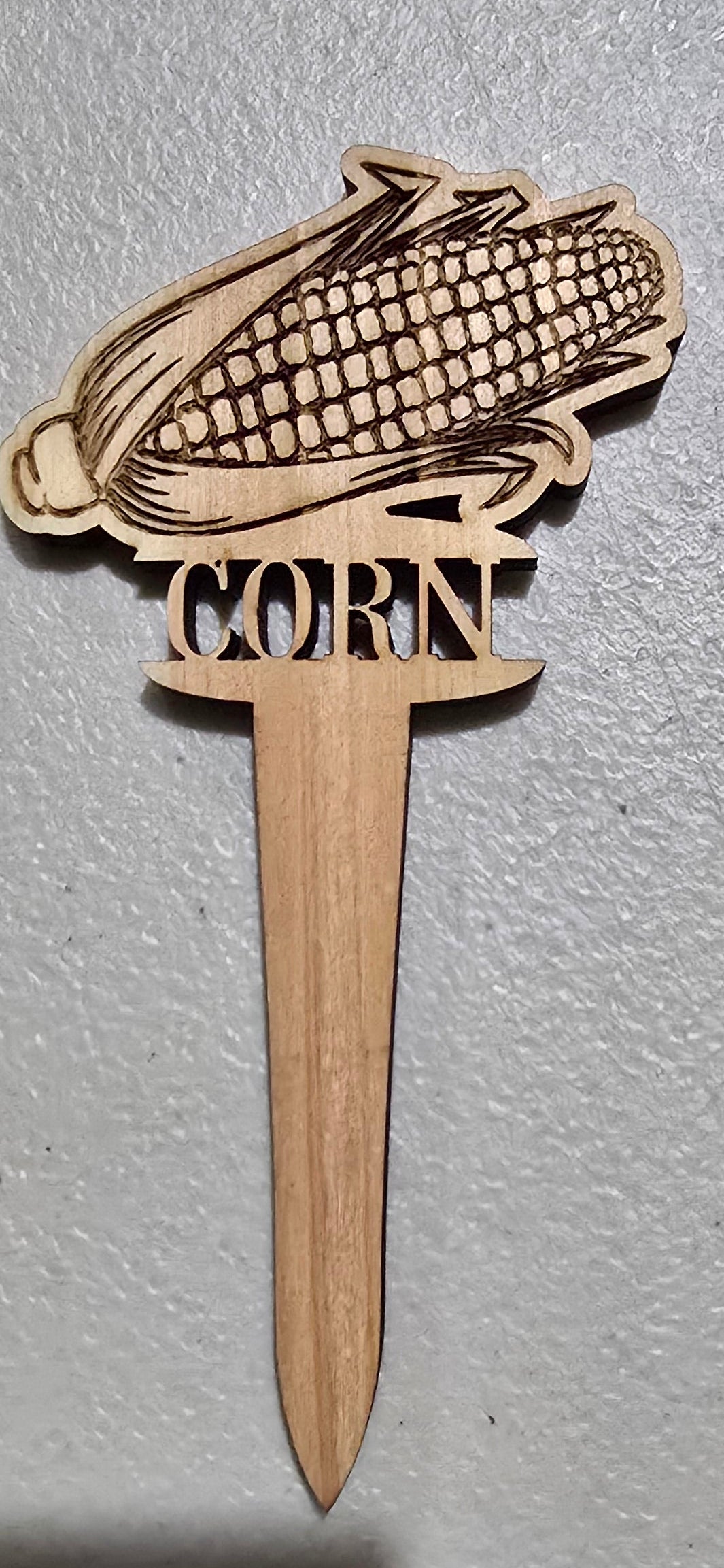 Wooden corn on the cob-shaped toothpick on a gray surface