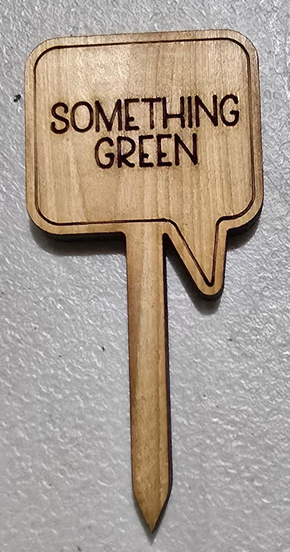 Wooden arrow-shaped sign with 'Something Green' text on a gray background