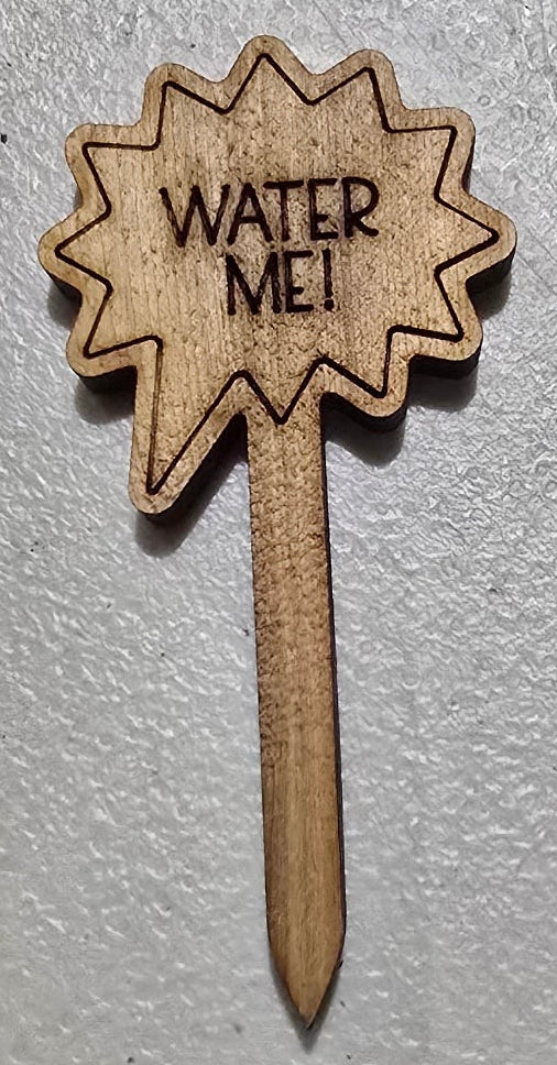 Wooden plant label with 'Water Me' text on a gray surface