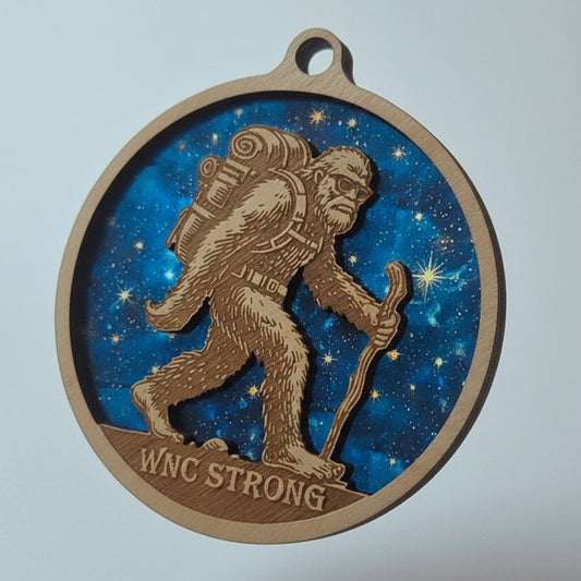 Medal with a Sasquatch design and 'WNC Strong' text against a starry night sky background.
