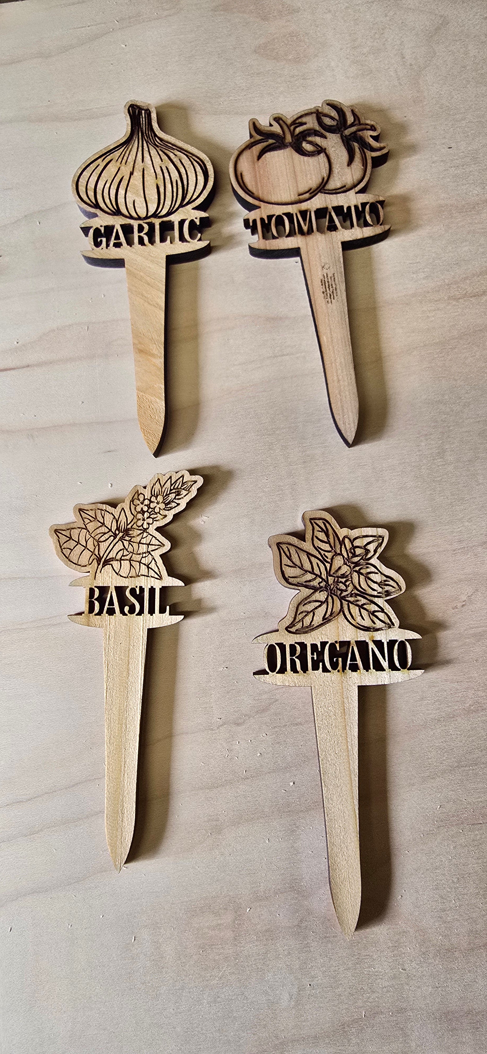 Set of wooden herb markers with plant illustrations and text on a wooden surface