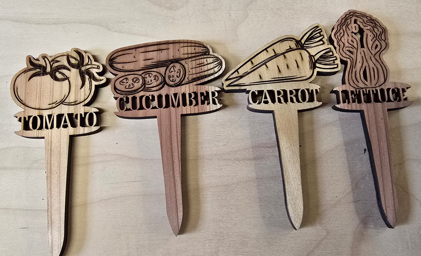 Wooden garden markers with vegetable illustrations and labels on a wooden surface