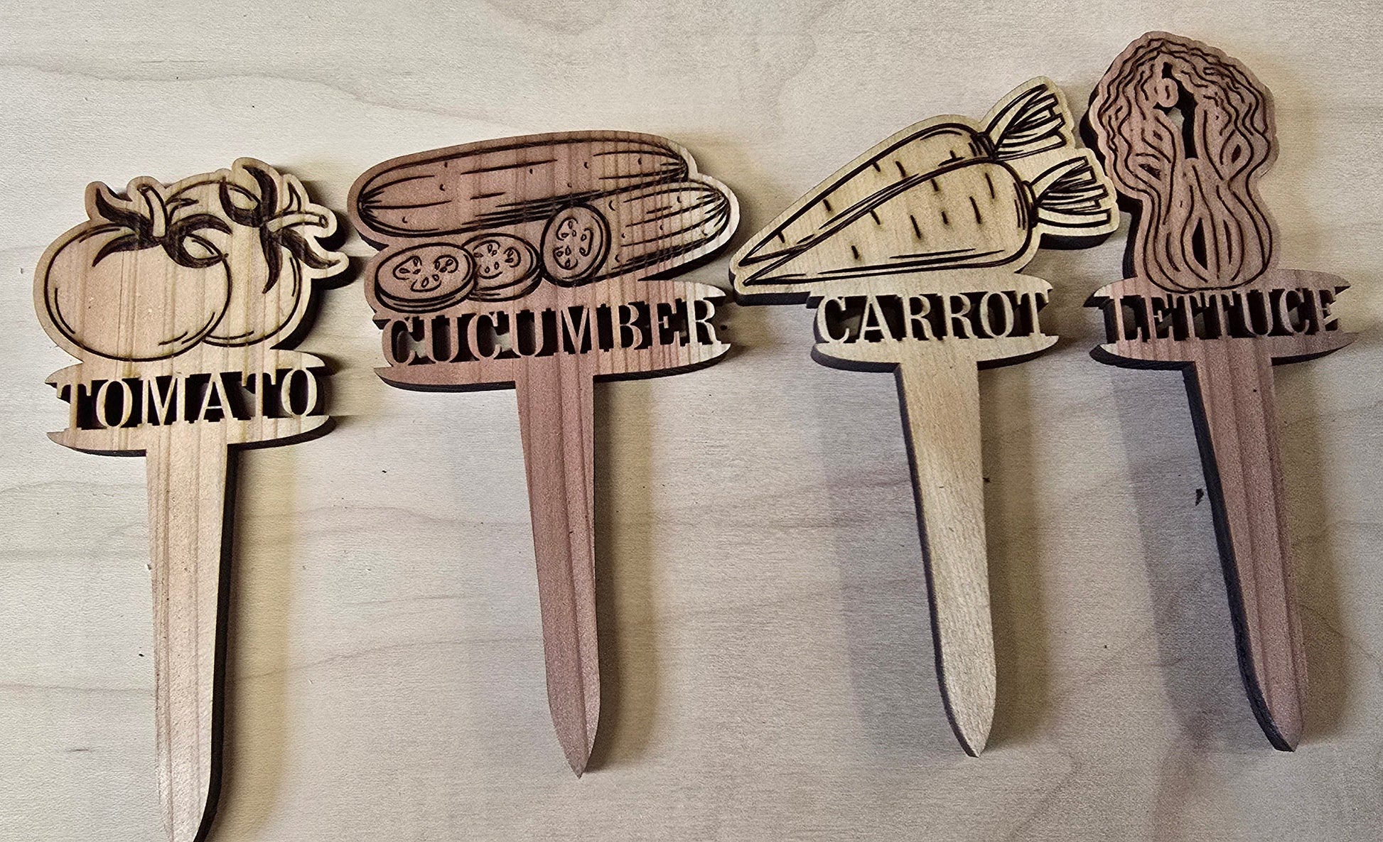 Wooden garden markers with vegetable illustrations and labels on a wooden surface